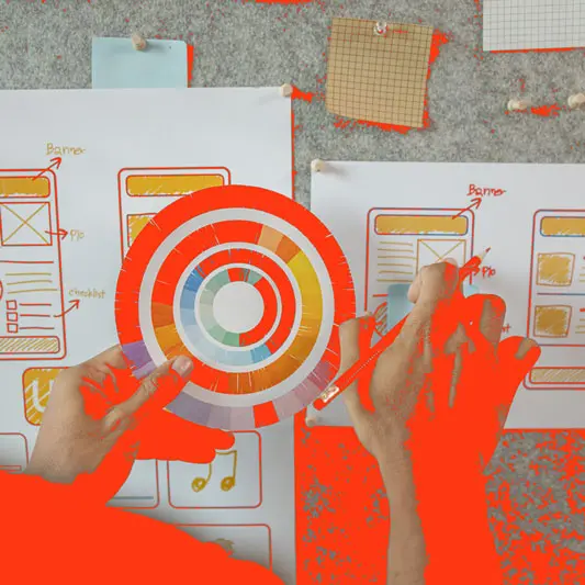 Manos trabajando en diseño web con paleta de colores y bocetos en Castellón