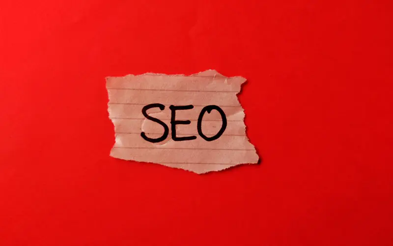 Consultor SEO Castellón con enfoque visual directo papel rasgado con la palabra SEO sobre fondo rojo, ideal para consultor SEO en Castellón