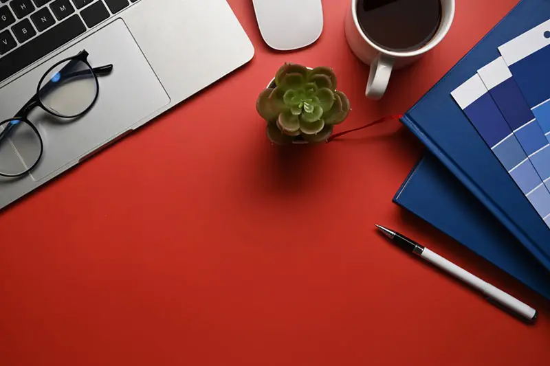 Espacio de trabajo de un desarrollador web en Castellón Mesa de trabajo con portátil, gafas, café y cuaderno de un desarrollador web en Castellón
