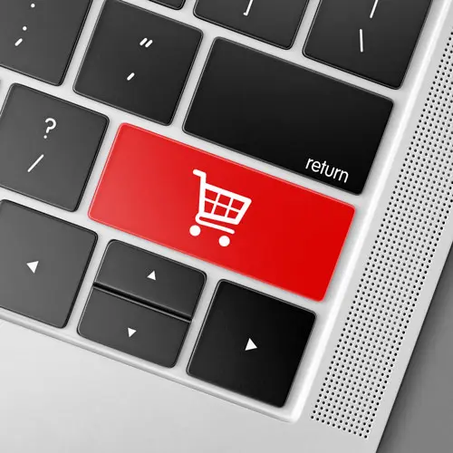 Tecla con carrito sobre teclado para diseño web e-commerce Tecla roja con icono de carrito en teclado, simbolizando diseño web para tiendas online