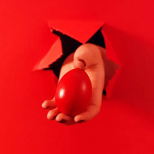 SEO estrategia creativa con impacto visual en rojo SEO estrategia. Mano saliendo de una pared roja ofreciendo un huevo rojo como metáfora de estrategia SEO